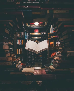 Ein Buch schwebt vor einer Bücherwand in einer Bibliothek.